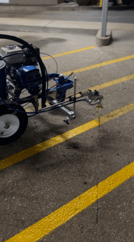 A worker spreading asphalt sealant with a special tool.