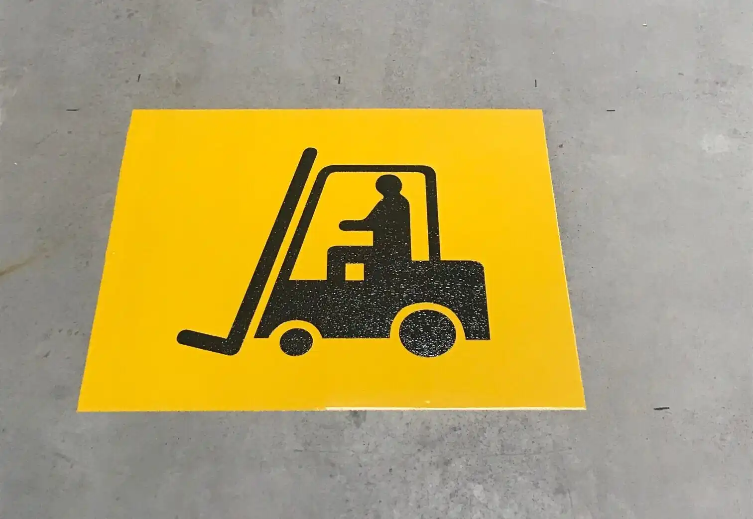 Custom stenciling on a warehouse floor, providing clear signage on industrial surfaces for improved safety and organization