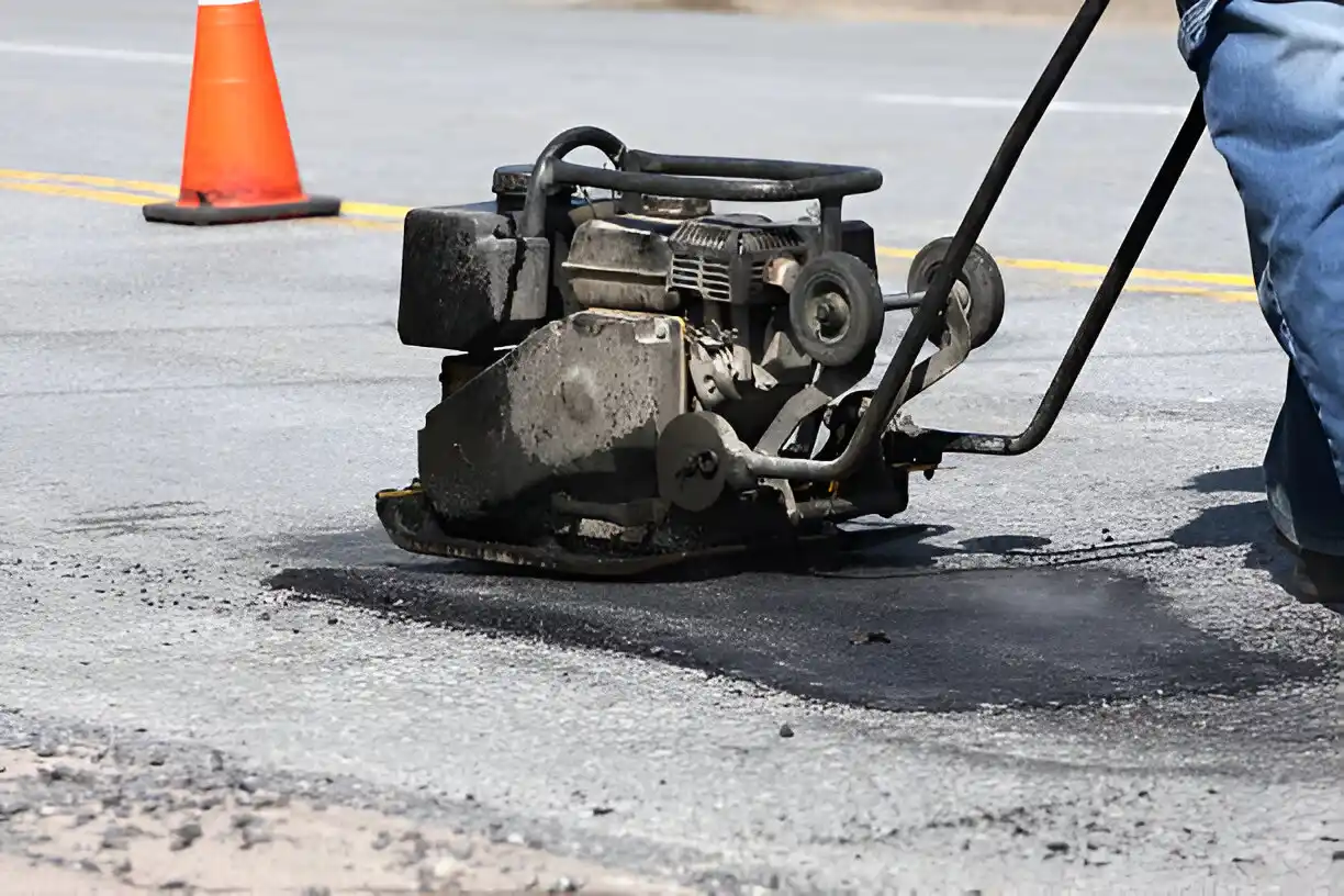 Man raking pothole repair compound and smoothing it
